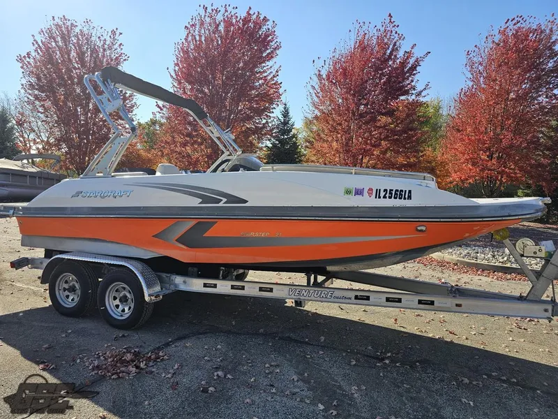 Slide: The Image of 2018 Starcraft Star Step 221 I/O boat on a trailer with autumn trees in the background. - 15