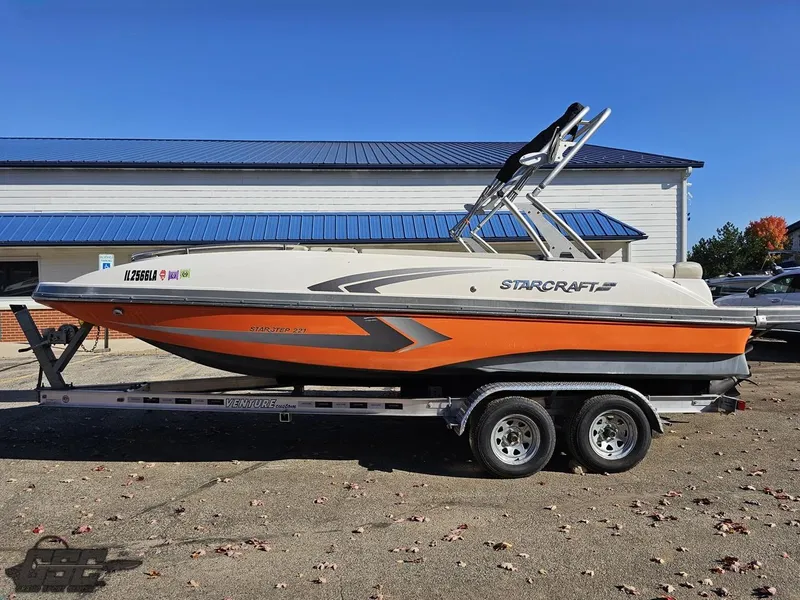Slide: The Image of 2018 Starcraft Star Step 221 I/O boat on a trailer, orange and white exterior. - 2