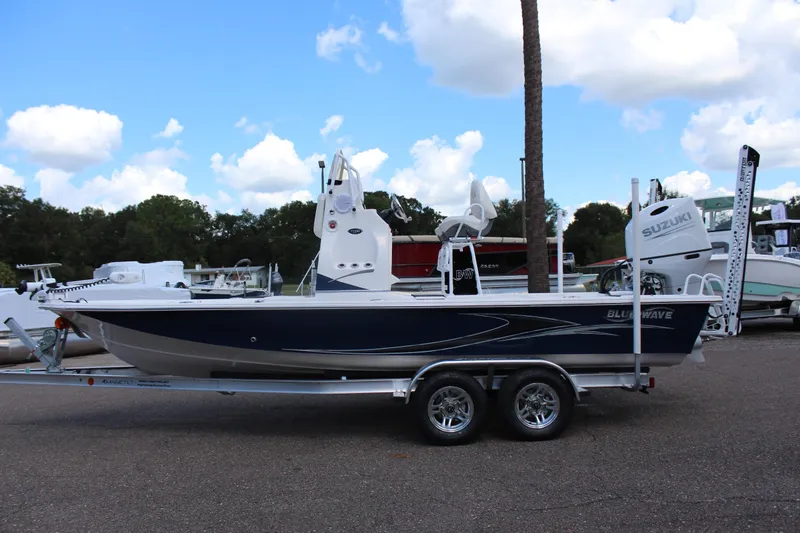 Slide: The Image of 2024 Blue Wave 2200 STL boat on a trailer in a marina. - 2