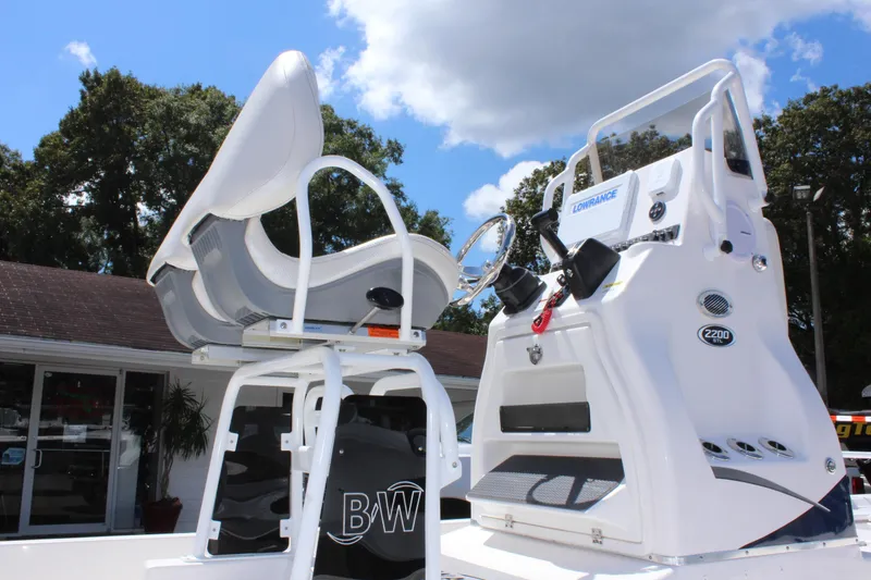 Slide: The Image of 2024 Blue Wave 2200 STL boat console and seating under a clear sky. - 6