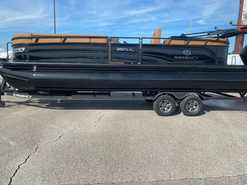 Slide: The Image of 2024 Regency 250 LE3 pontoon boat on trailer, black exterior. - 0