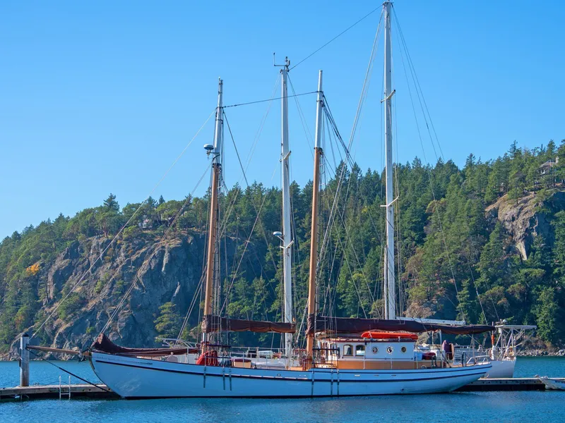 The Image of Custom 1997 Prothero & Franken sailboat docked by forested cliffs. - 0