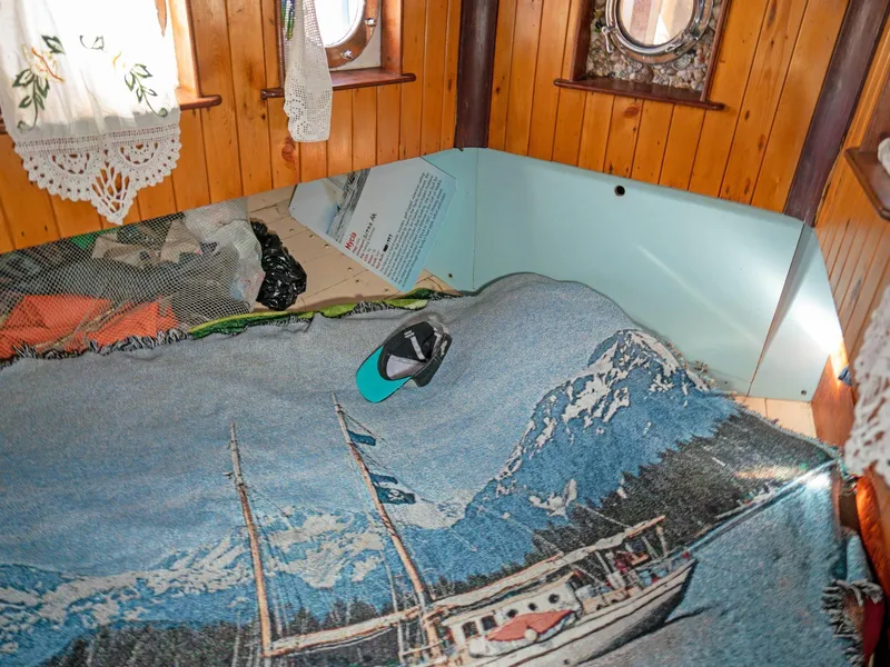 Slide: The Image of Cozy boat cabin interior with nautical-themed blanket, wooden walls, and porthole windows. - 6