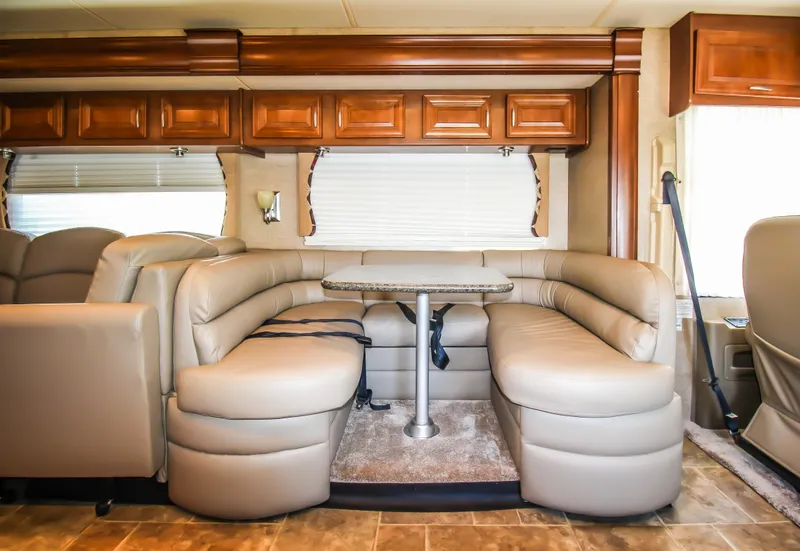 Slide: The Image of 2012 Thor 37DT RV interior with leather seating and dining table. - 11