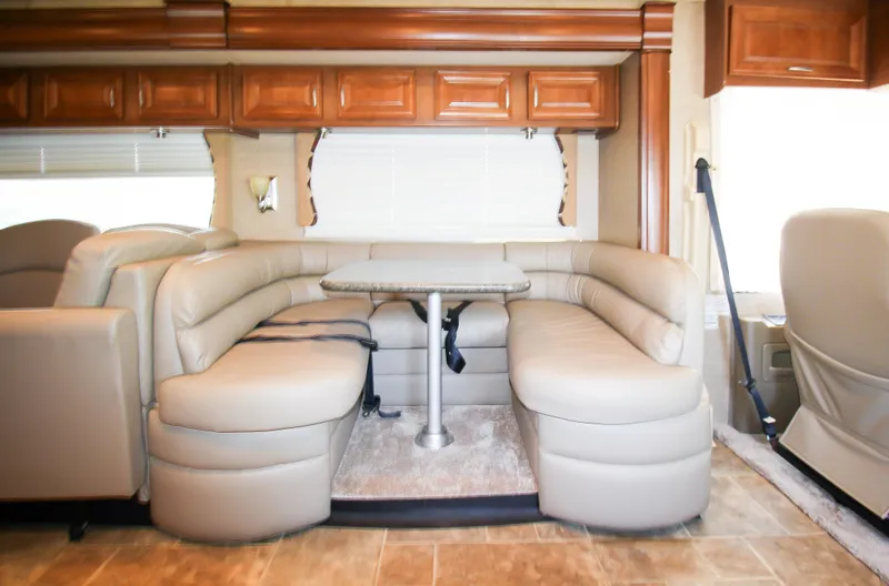 Slide: The Image of 2012 Thor 37DT RV interior with leather seating and dining table. - 12