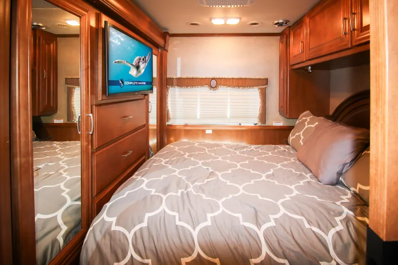 Slide: The Image of 2012 Thor 37DT motorhome bedroom with TV, mirrored closet, and cozy bed. - 13