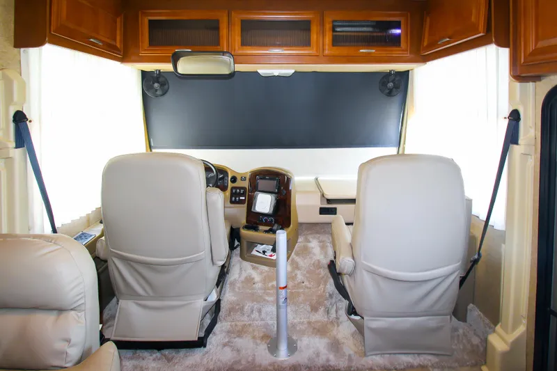 Slide: The Image of 2012 Thor 37DT RV interior, front driver and passenger seats, dashboard, and overhead storage. - 14