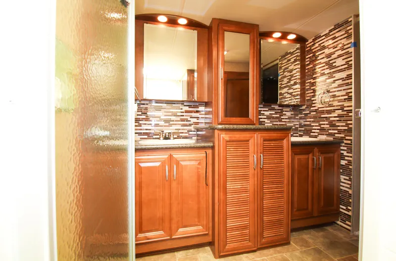 Slide: The Image of 2012 Thor 37DT RV bathroom with wooden cabinets and modern tile backsplash. - 19