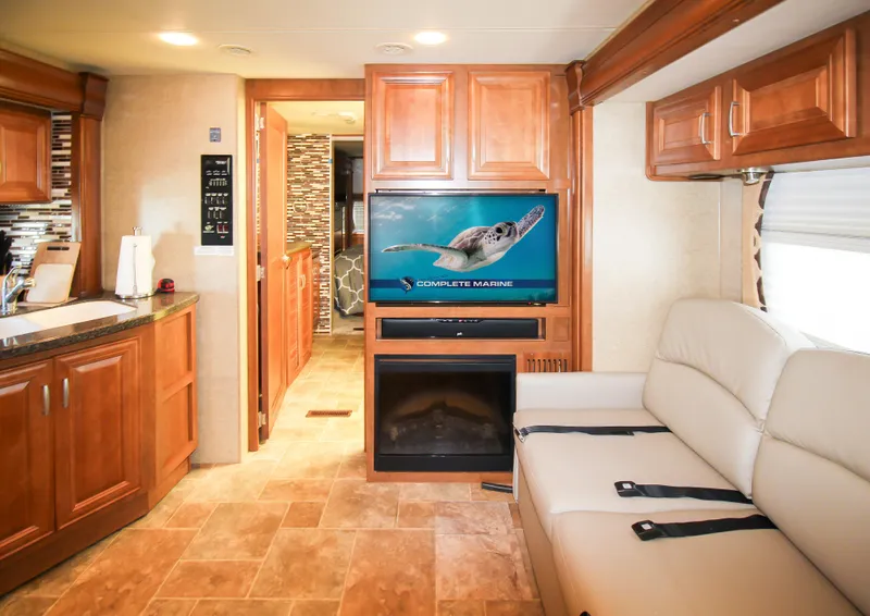 Slide: The Image of 2012 Thor 37DT RV interior with kitchen, TV, fireplace, and sofa. - 3