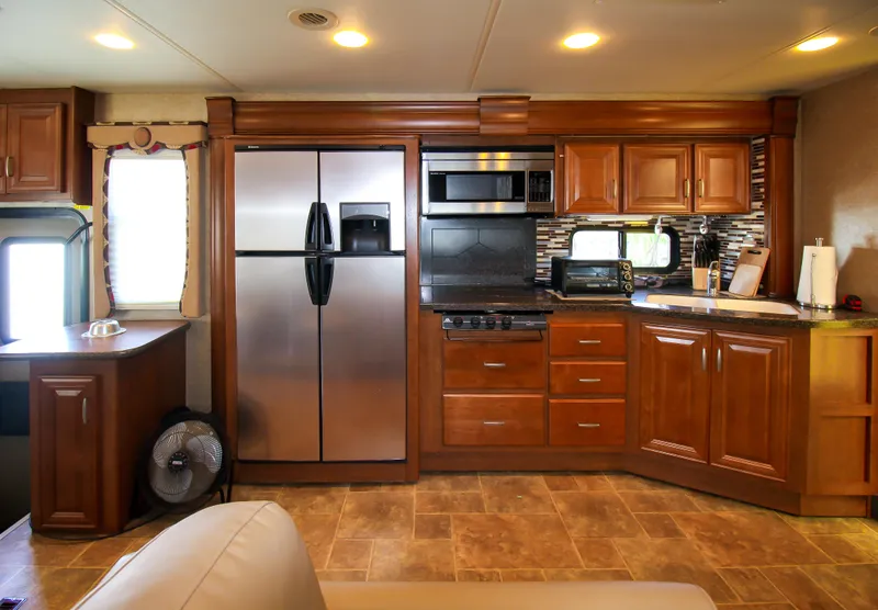 Slide: The Image of Modern kitchen in 2012 Thor 37DT RV with stainless steel appliances and wooden cabinets. - 6