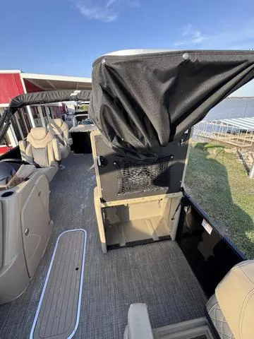 Slide: The Image of 2023 Starcraft CX23FD pontoon boat interior with seating and canopy, docked by the water. - 23