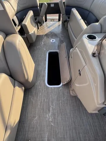 Slide: The Image of 2023 Starcraft CX23FD boat interior with open storage compartment and beige seating. - 24