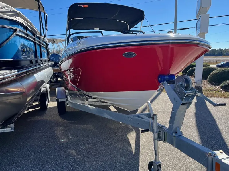Slide: The Image of 2024 Bayliner VR4 boat with red hull on a trailer, parked outdoors. - 2