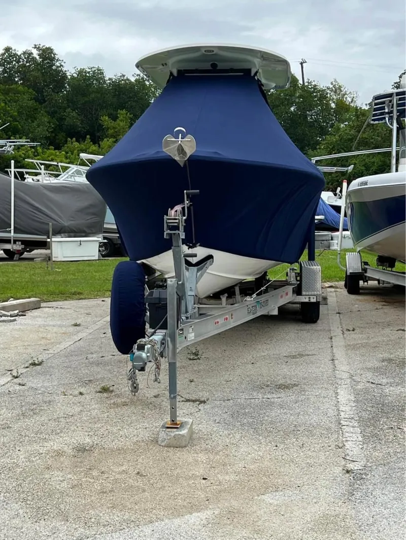 Slide: The Image of 2018 Sea Hunt 235 boat with blue cover on trailer in storage lot. - 17