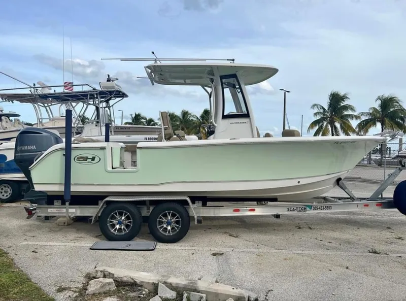 Slide: The Image of 2018 Sea Hunt 235 boat on a trailer, parked near palm trees. - 3
