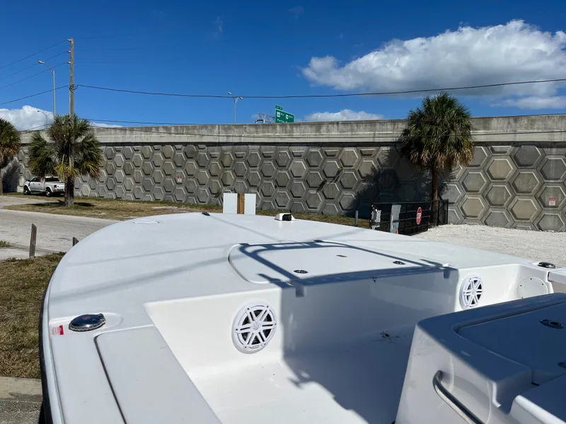 Slide: The Image of 2025 Tidewater 25 TPC boat with white deck and speakers, parked near a concrete wall. - 9