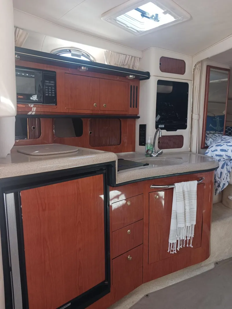 Slide: The Image of 2001 Sea Ray Sundancer interior with wood cabinetry, kitchenette, and cozy sleeping area. - 4