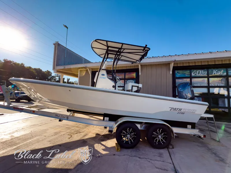 Slide: The Image of 2024 Pathfinder TRS 2200 boat on trailer outside marine shop, sunny day. - 1