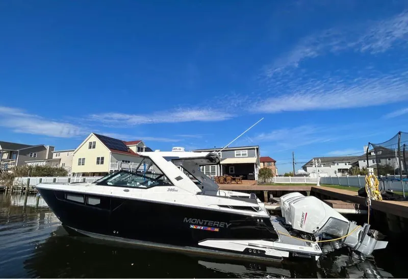Slide: The Image of 2019 Monterey 385 SE boat docked near waterfront homes under a clear blue sky. - 1