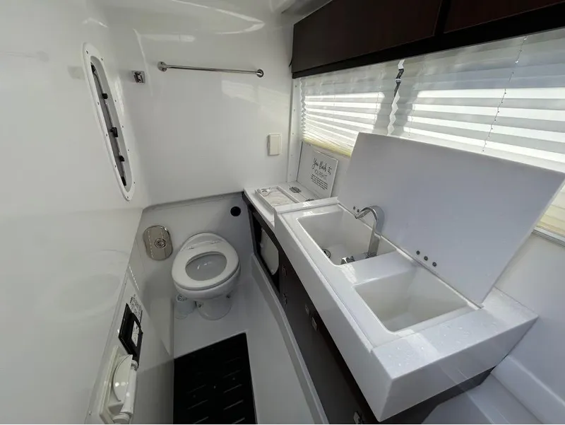 Slide: The Image of 2019 Monterey 385 SE boat bathroom with toilet, sink, and window blinds. - 18