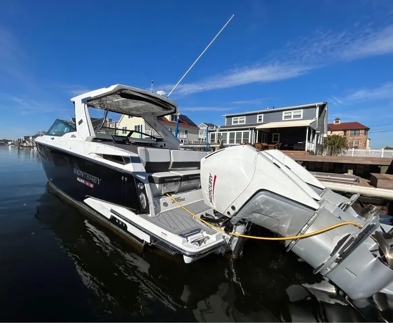 Slide: The Image of 2019 Monterey 385 SE boat docked by waterfront homes under clear blue sky. - 2