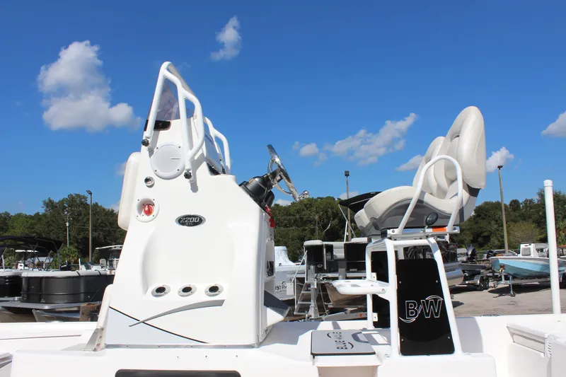 Slide: The Image of 2024 Blue Wave 2200 STL boat console and seating under clear blue sky. - 22