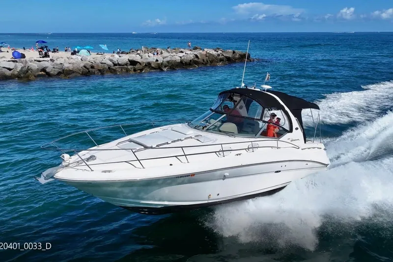 The Image of 2007 Sea Ray Sundancer 320 cruising near a rocky shoreline on a sunny day. - 0