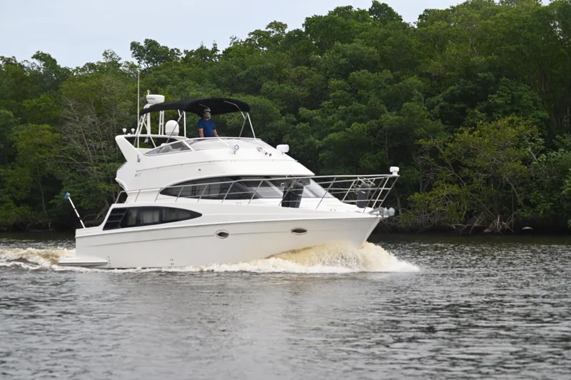 The Image of 2005 Carver 36 Super Sport yacht cruising on a river with lush green trees in the background. - 0