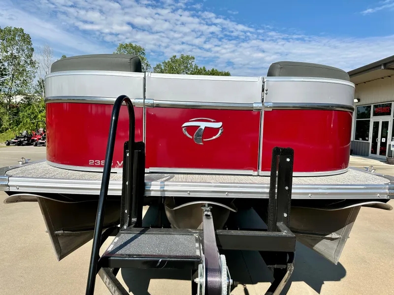 Slide: The Image of 2023 Tahoe Pontoon 23FT Cascade Versatile Rear Bench, red exterior, docked on trailer. - 2