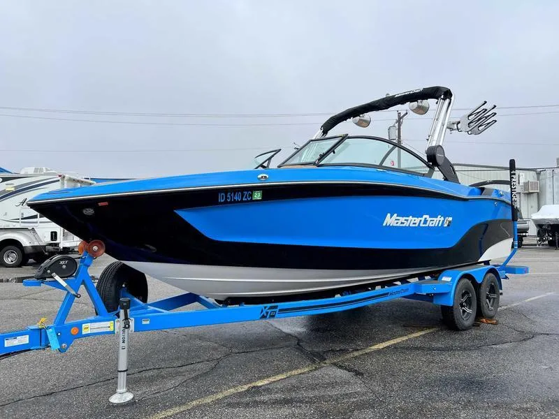 Slide: The Image of 2023 MasterCraft XT23 boat on a blue trailer in a parking lot. - 12