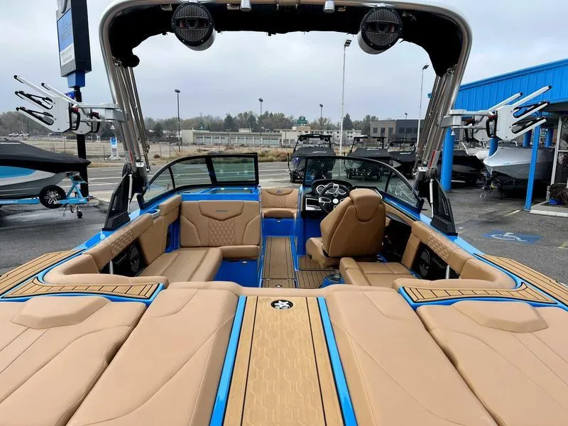 Slide: The Image of 2023 MasterCraft XT23 boat interior with tan and blue seating, wakeboard racks, and modern dashboard. - 5