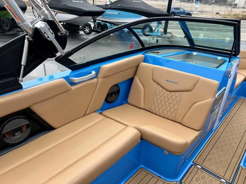 Slide: The Image of 2023 MasterCraft XT23 boat interior with tan leather seats and blue accents. - 6