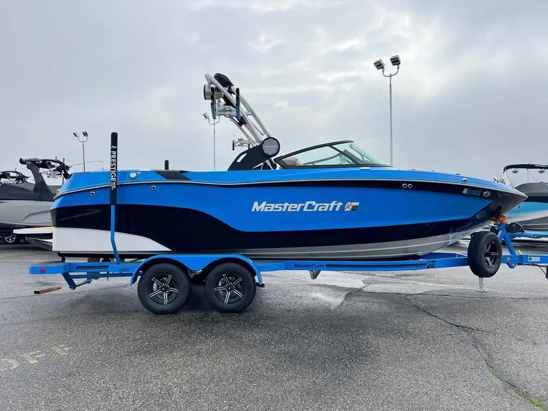 Slide: The Image of 2023 MasterCraft XT23 boat in blue and black on a trailer. - 8