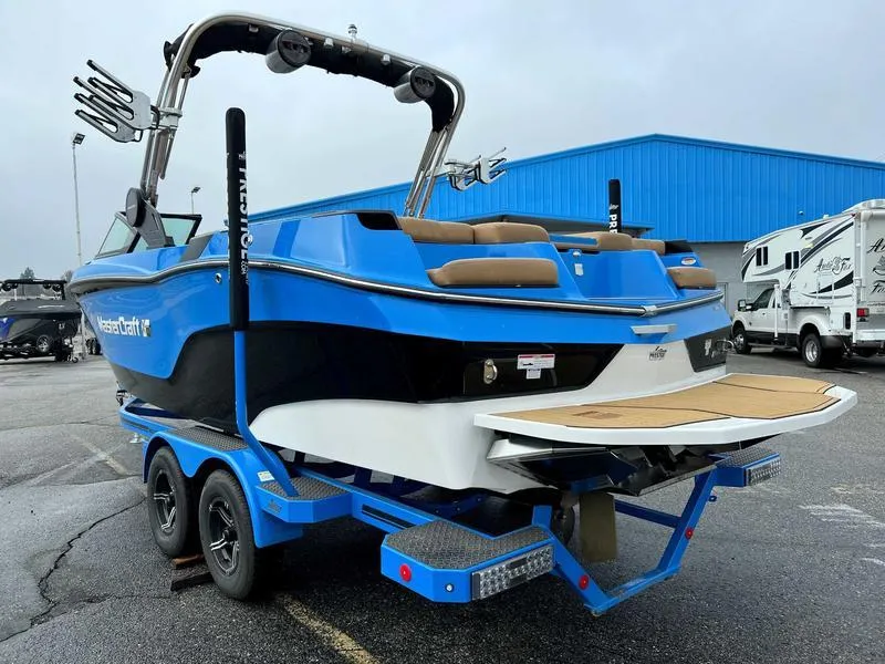 Slide: The Image of 2023 MasterCraft XT23 boat on trailer, blue and black exterior, rear view. - 9
