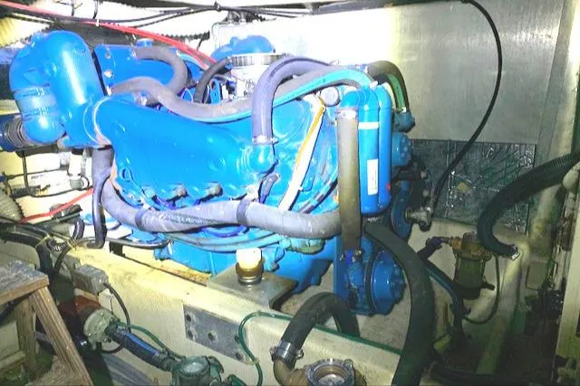 Slide: The Image of 1984 Uniflite Double Cabin engine compartment with blue engine and various hoses. - 43