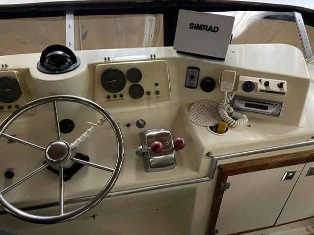 Slide: The Image of 1984 Uniflite Double Cabin helm with steering wheel, gauges, and Simrad navigation system. - 5