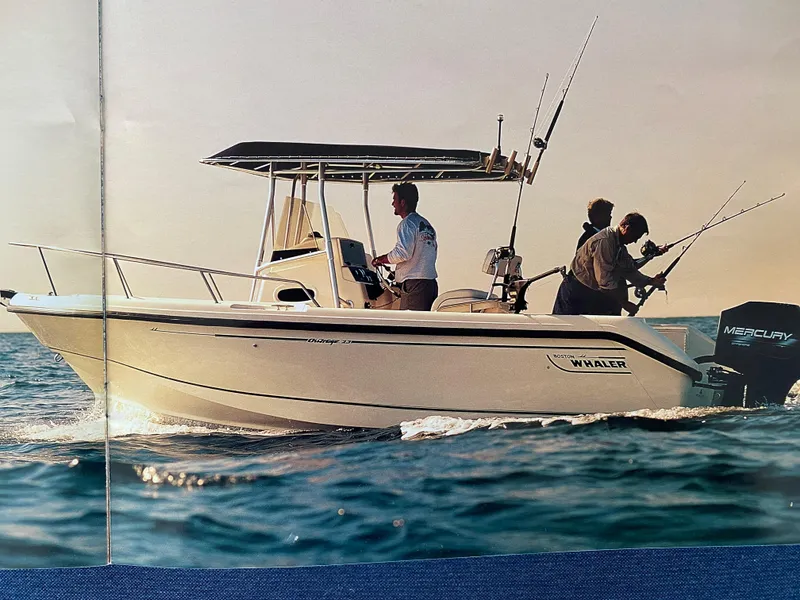 Slide: The Image of 2000 Boston Whaler 23 Outrage boat on the water with three people fishing. - 25