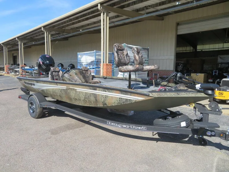 Slide: The Image of 2024 Ranger RT188P fishing boat on trailer, camo seats, outboard motor, parked outdoors. - 2