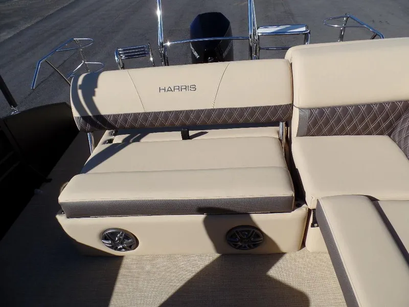 Slide: The Image of 2024 Harris Sunliner 230 boat seating area with beige upholstery and built-in speakers. - 11