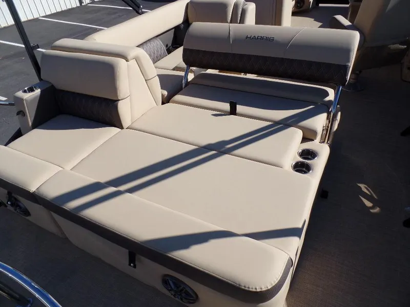 Slide: The Image of 2024 Harris Sunliner 230 boat with beige cushioned seating and cup holders. - 16