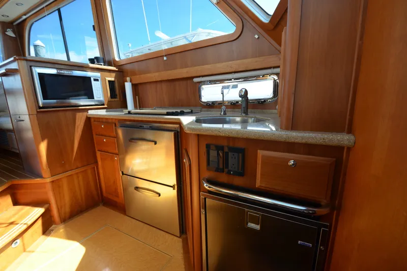 Slide: The Image of 2014 Sabre 42 Salon Express kitchen with wood cabinetry, stainless steel appliances, and a window view. - 23