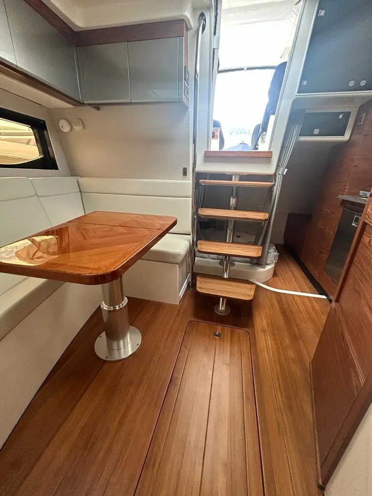 Slide: The Image of 2024 Boston Whaler 405 Conquest interior with wooden flooring and dining area. - 8