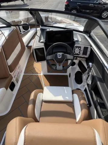 Slide: The Image of 2023 Malibu 26 LSV boat interior with brown and white seating, modern dashboard. - 10