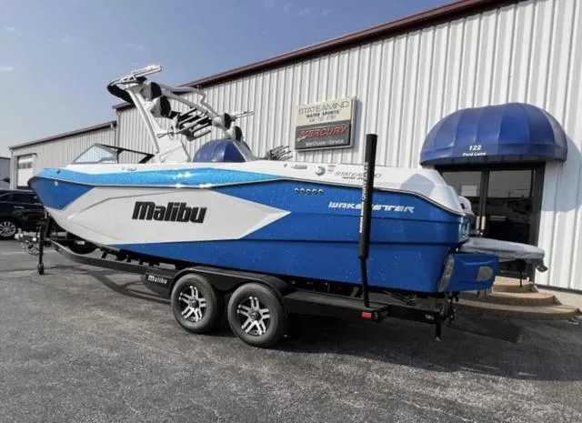 Slide: The Image of 2023 Malibu 26 LSV boat in blue and white, parked on a trailer outside a dealership. - 3