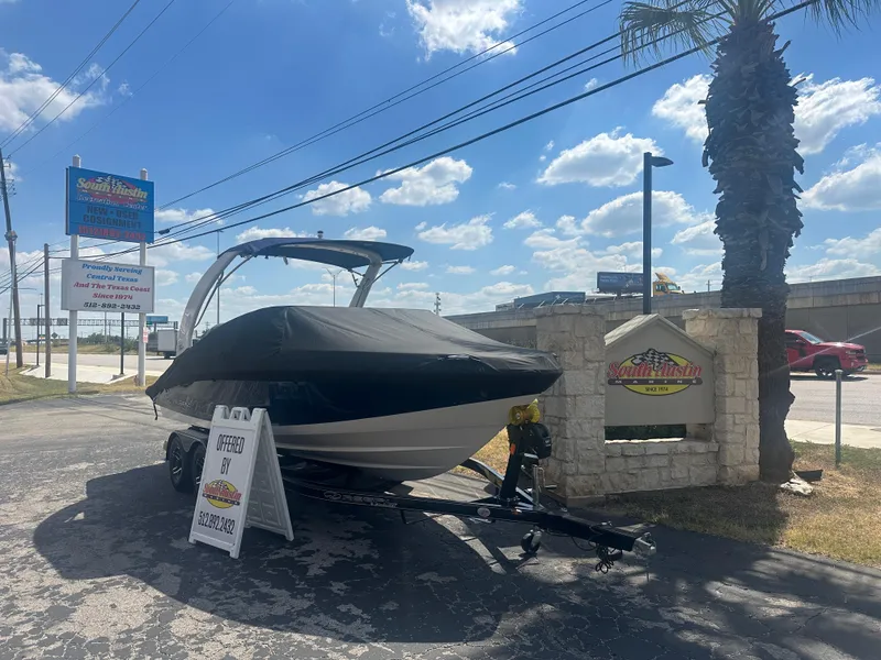 Slide: The Image of 2023 Regal 21 OBX boat on trailer at dealership under sunny sky. - 1