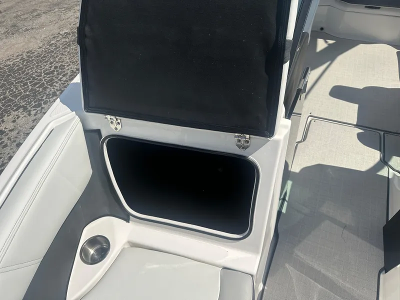 Slide: The Image of 2023 Regal 21 OBX boat interior storage compartment with open lid and cup holder. - 18