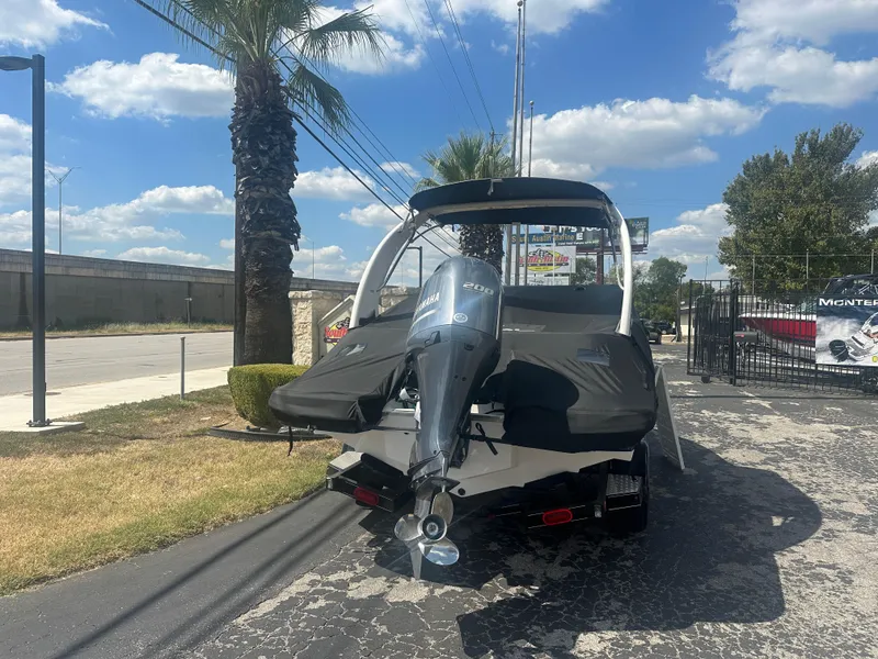 Slide: The Image of 2023 Regal 21 OBX boat with outboard motor on a sunny day, parked near palm trees. - 2