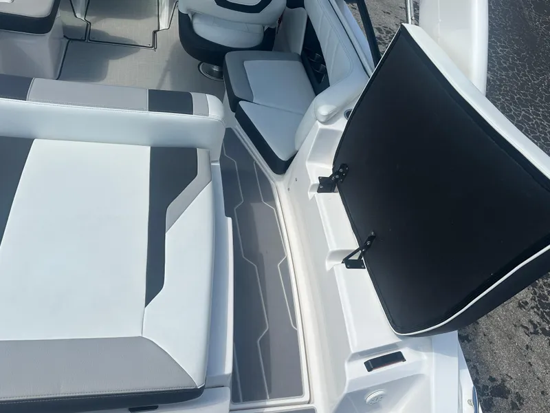 Slide: The Image of 2023 Regal 21 OBX boat interior with white and gray seating and open storage compartment. - 34