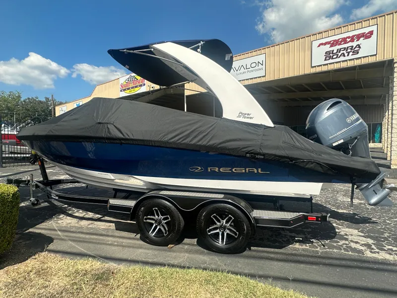 Slide: The Image of 2023 Regal 21 OBX boat with cover on trailer, parked outside dealership. - 4