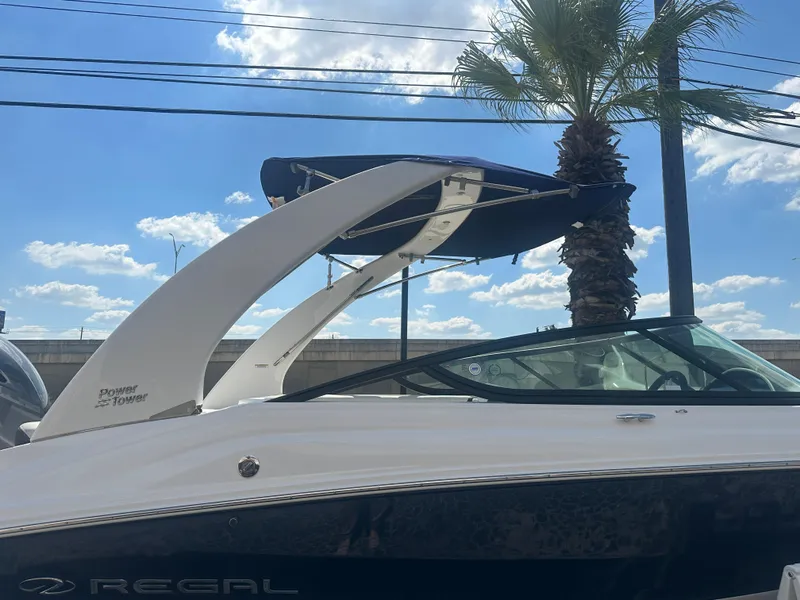 Slide: The Image of 2023 Regal 21 OBX boat with tower, parked under a sunny sky with palm trees. - 45